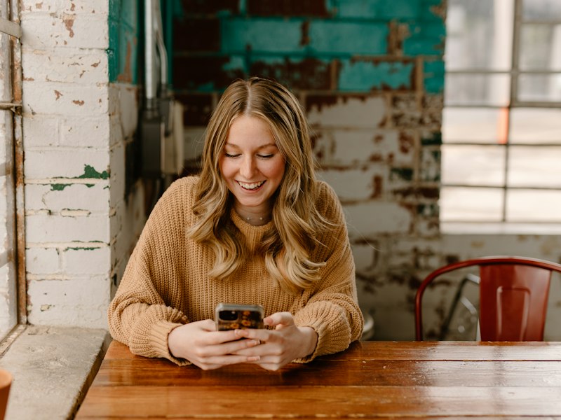 Woman signing up on her phone at a café